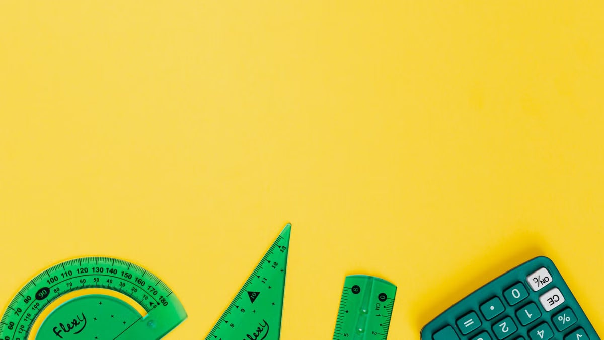 Vibrant school accessories including calculator and rulers against yellow backdrop.